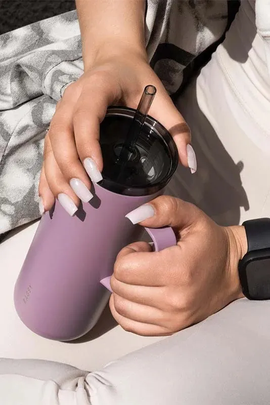 Moteris geria iš alyvinio MOSHI Tumbler per šiaudelį
